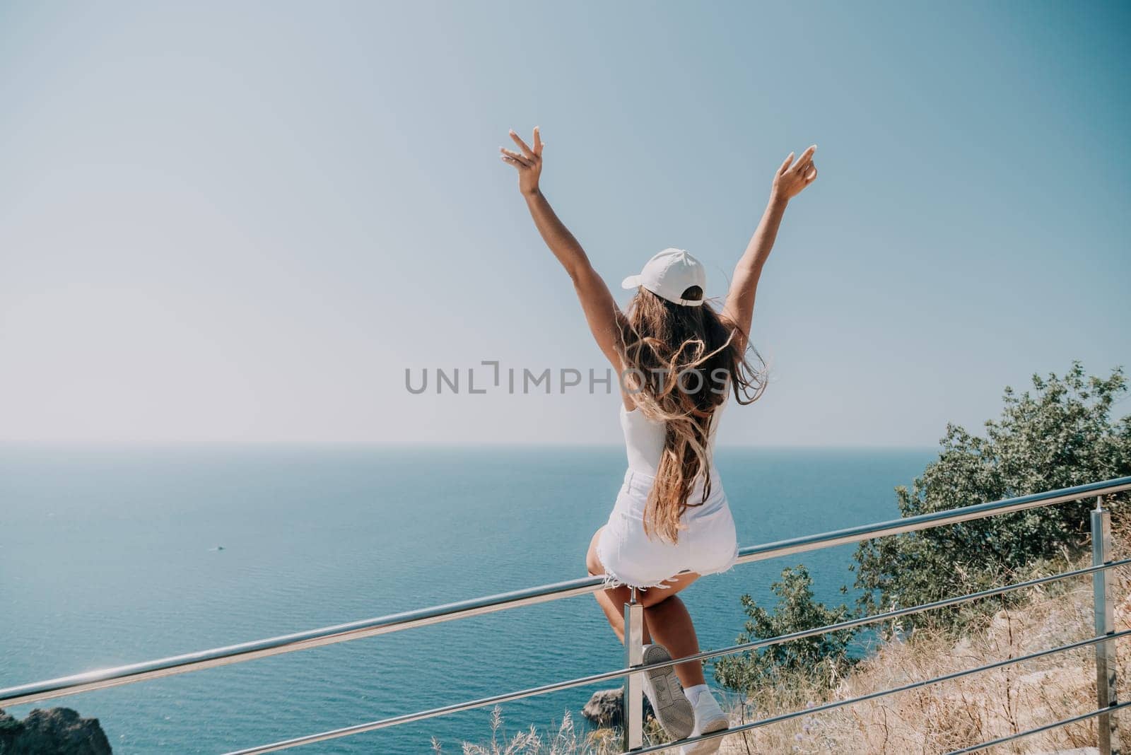 Woman summer travel sea. Happy tourist enjoy taking picture outdoors for memories. Woman traveler posing over sea bay surrounded by volcanic mountains, sharing travel adventure journey by panophotograph