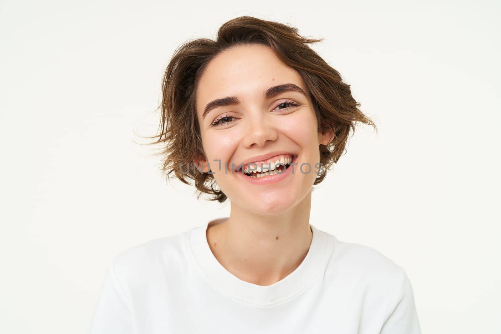 Close up portrait of brunette woman laughing and smiling, express genuine emotions, posing against white studio background.