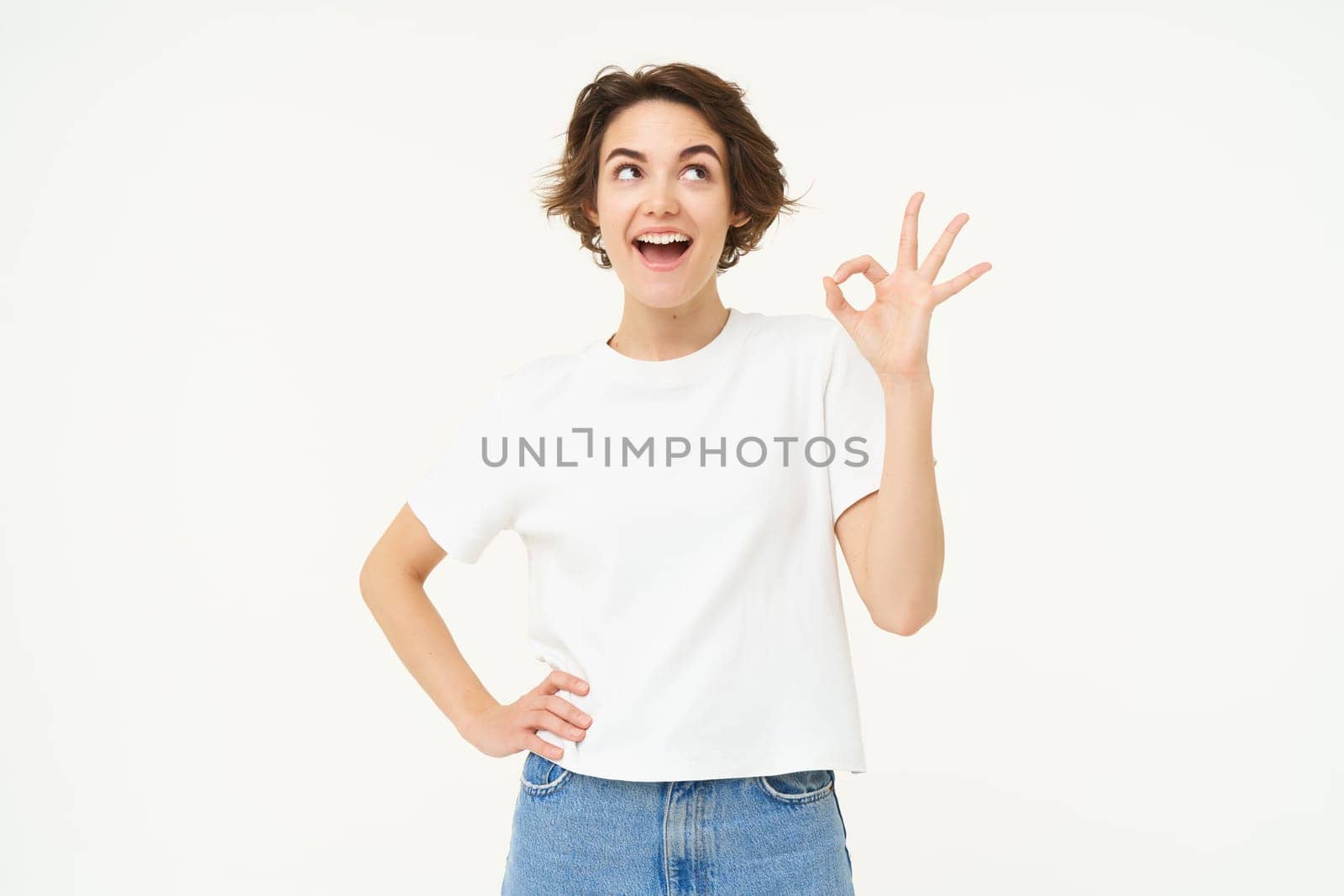 No problem, excellent. Young happy woman shows ok, okay gesture, nod in approval, recommending something good, standing over white background.