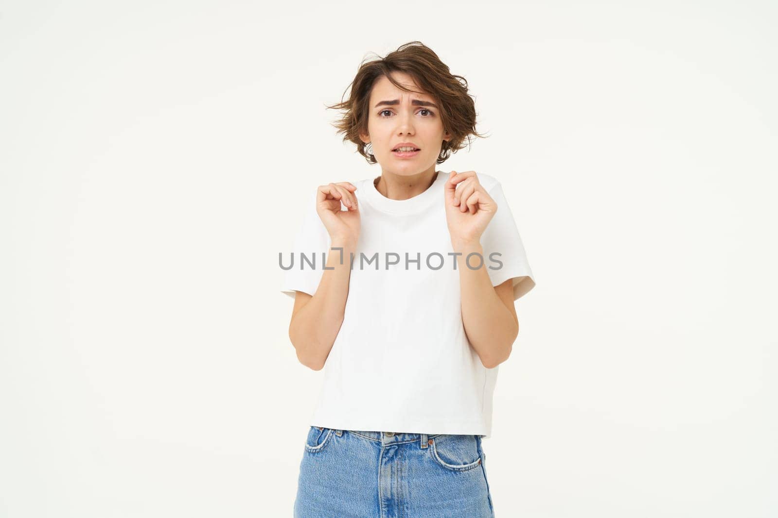 Image of woman with scared face, looks frightened, worried, trembling from fear, isolated against white background.