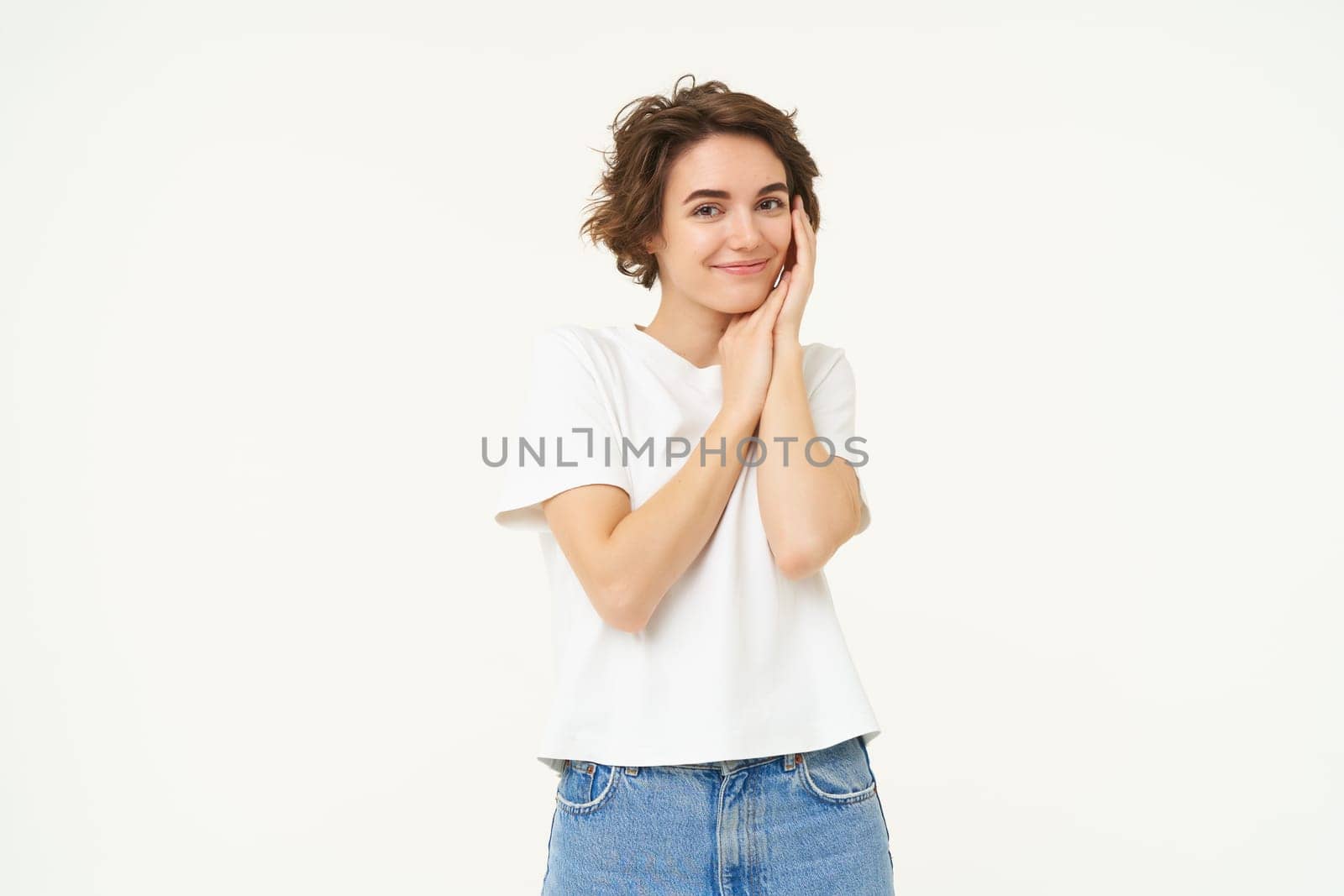 Portrait of cute brunette woman, looking with admiration and excitement, standing over white background.