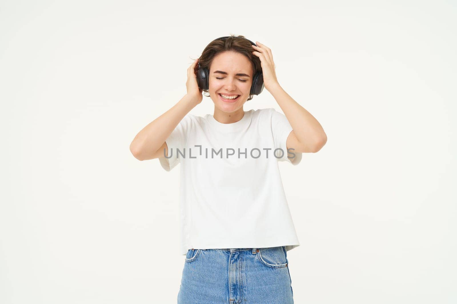 Portrait of smiling young woman, listening to music, enjoying dancing to favourite song, isolated on white background.