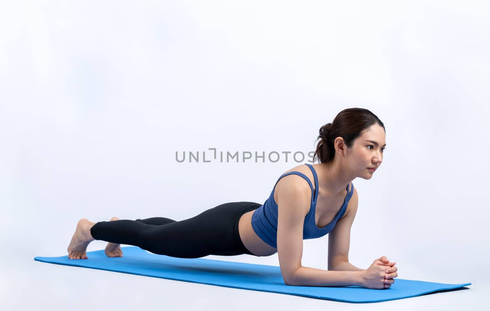 Fit young asian woman planing on exercising mat. Healthy lifestyle workout training routine on isolated background. Balance and endurance exercising concept. Vigorous