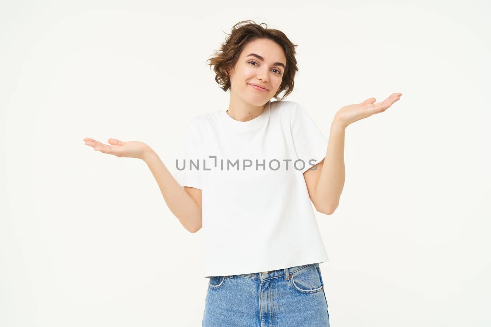 Woman shrugs her shoulders, looks clueless, doesnt know anything, stands confused against white background.