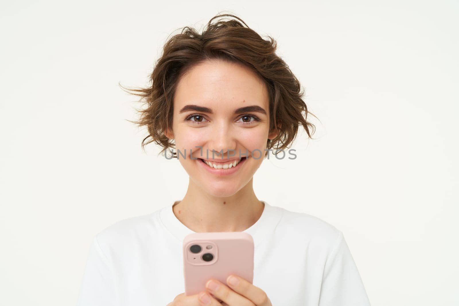 Technology concept. Young woman using her mobile phone, holding smartphone and smiling, using app, browsing social media, doing online shopping, isolated over white background.