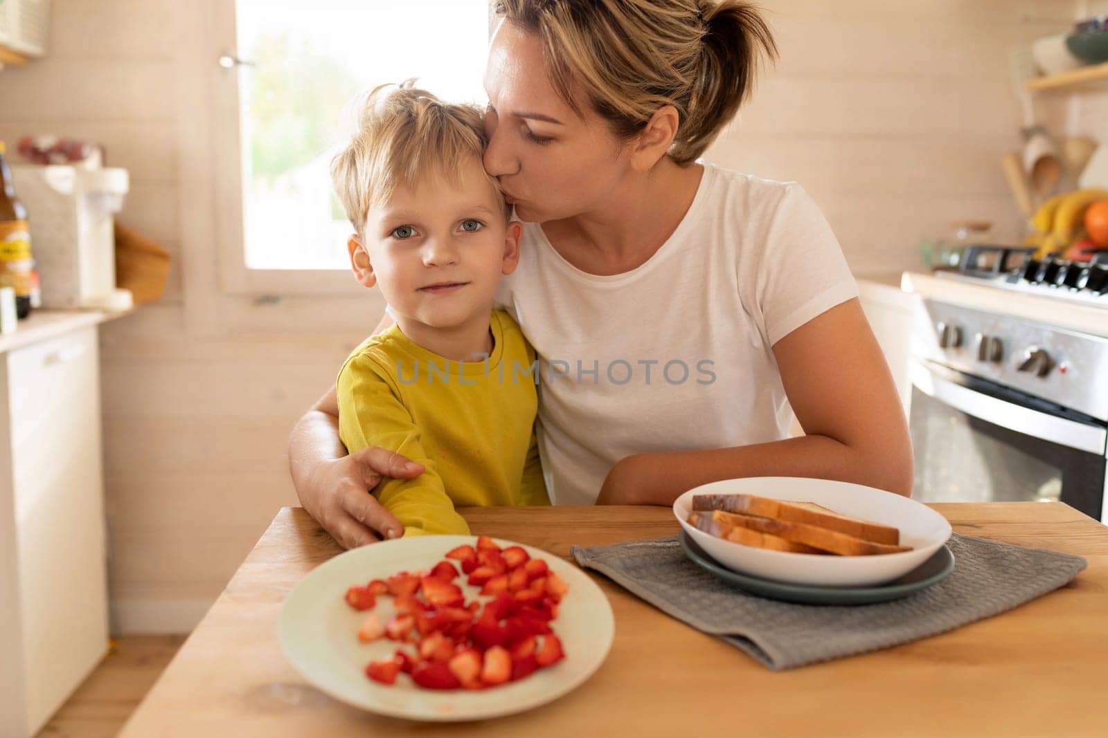 happy mother and little son preparing toast with strawberries for breakfast by TRMK