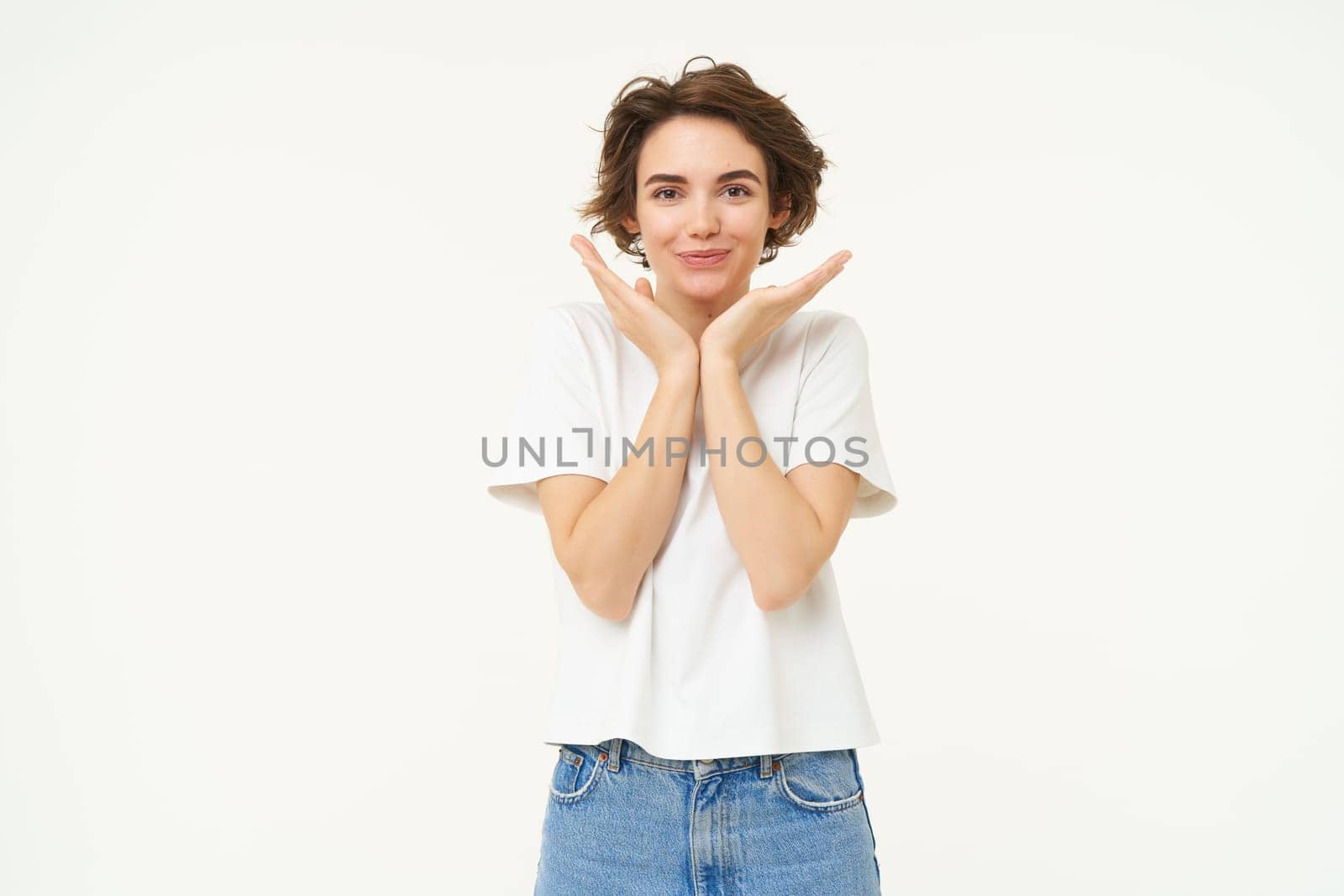 Portrait of cute brunette woman, looking with admiration and excitement, standing over white background.