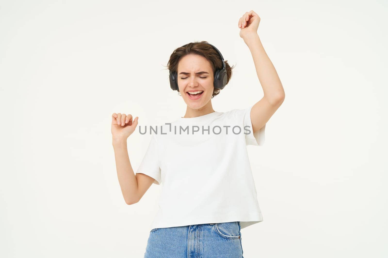 Portrait of smiling young woman, listening to music, enjoying dancing to favourite song, isolated on white background.