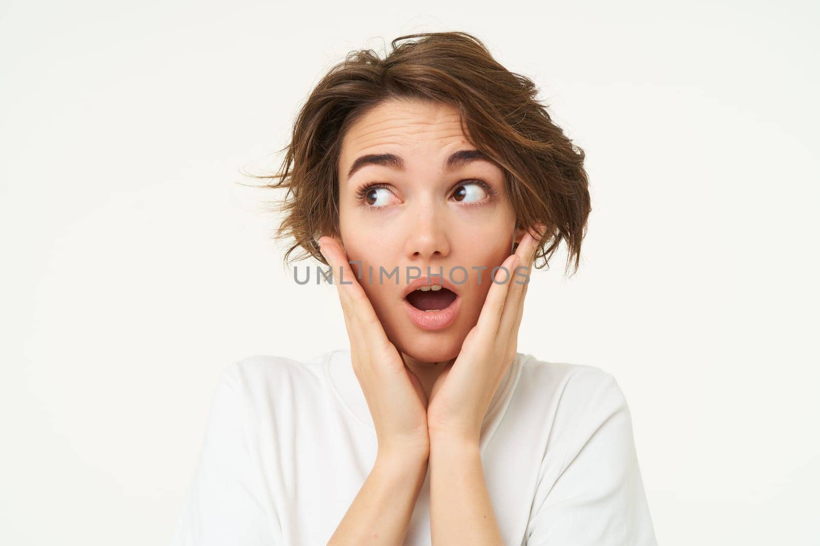 Fantastic news. Portrait of amazed young woman, looks surprised, gasps impressed, stands over white background.