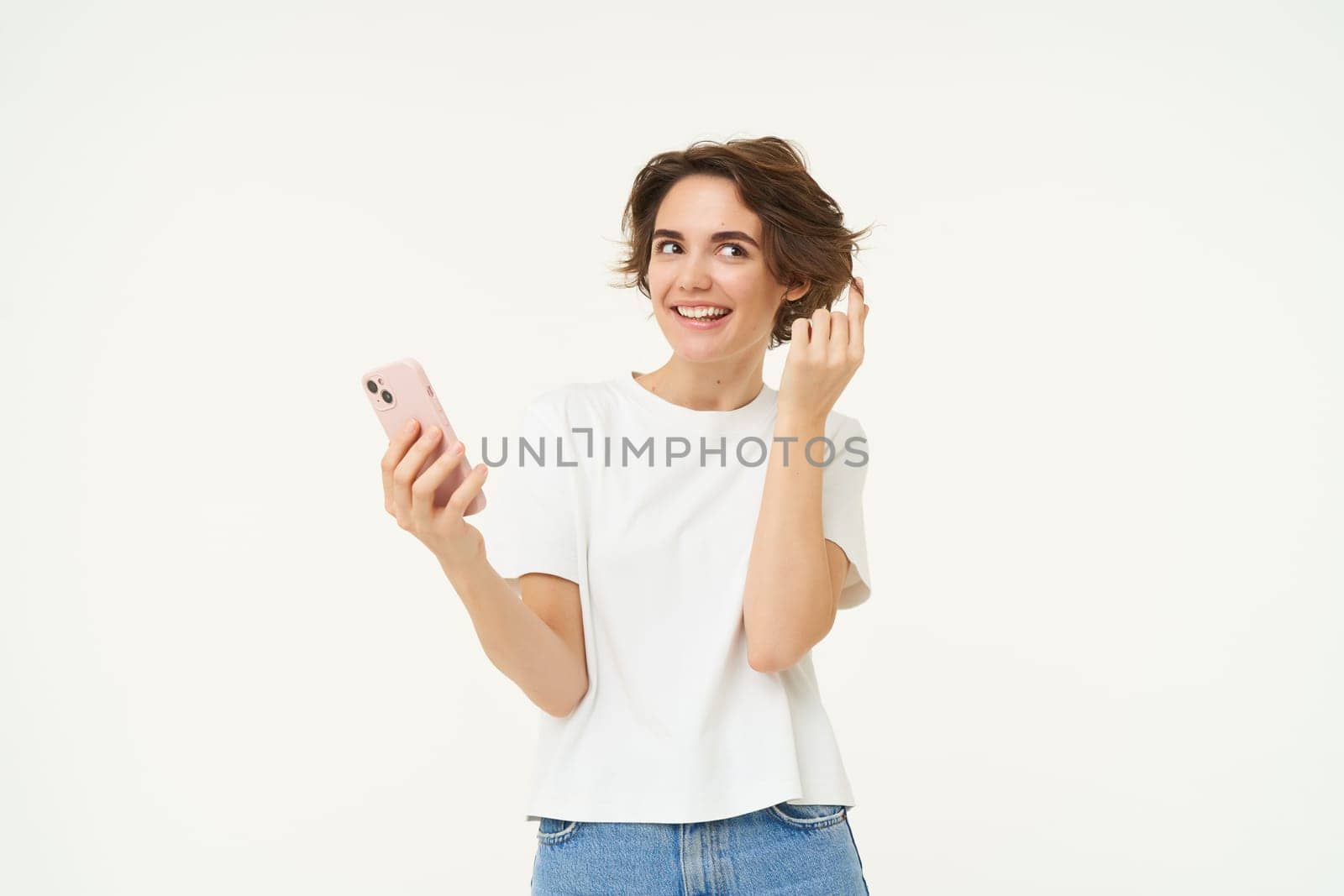 Technology and people. Happy brunette woman with mobile phone, smiling and laughing, standing over white background. Copy space