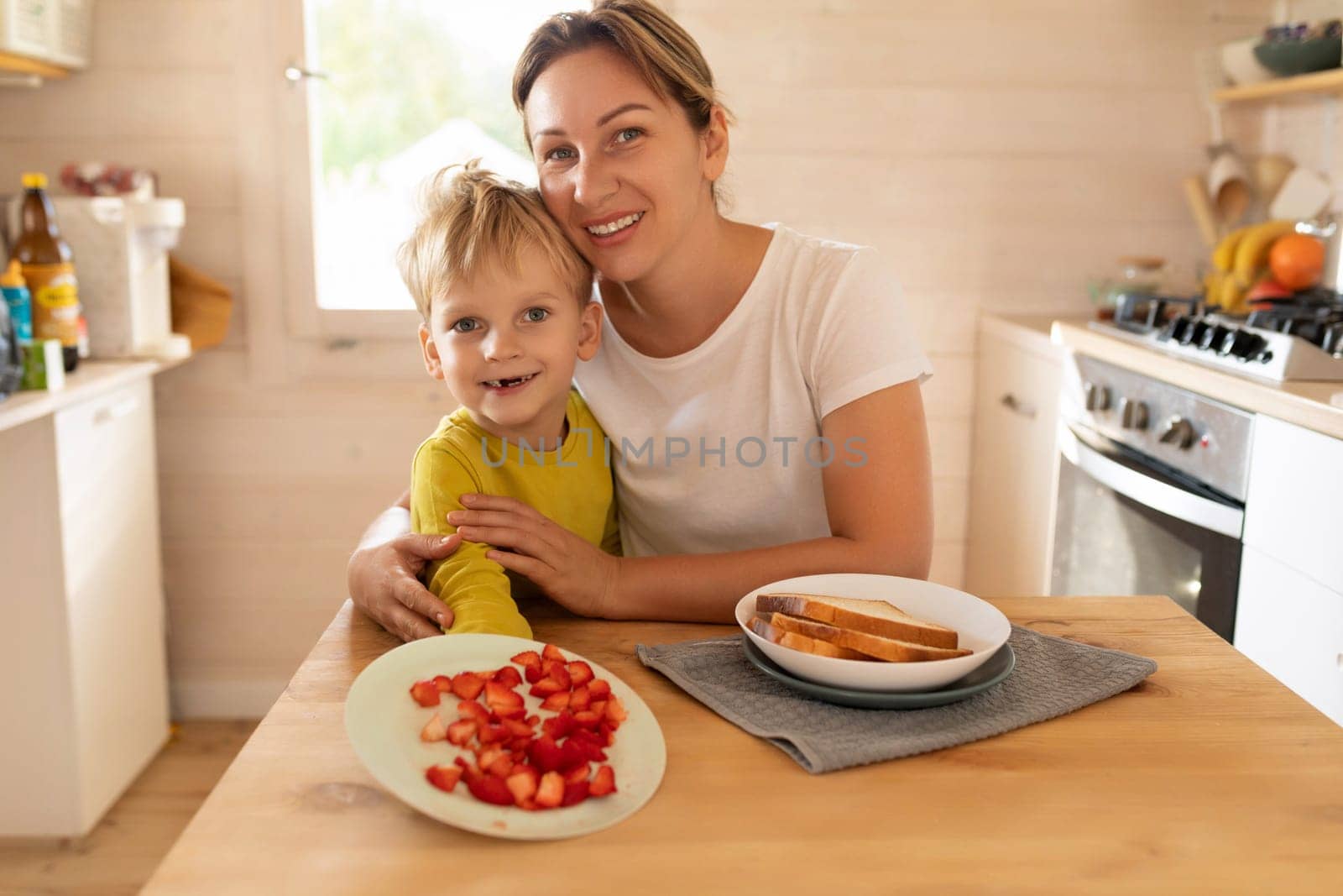 lifestyle concept, young mother and son sitting at the table in the kitchen with plates of food.