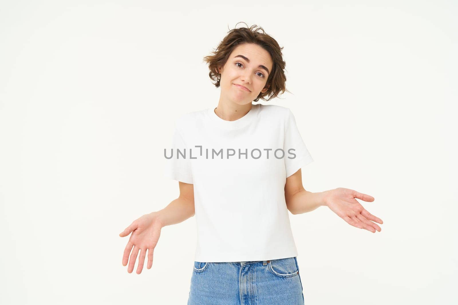 Portrait of brunette woman shrugging shoudlers, dont know, standing unaware, clueless, cant help, stands over white background.