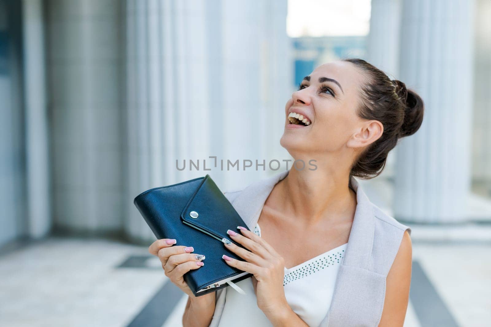 Successful businessman or entrepreneur smiling holding notepad while walking outdoor. City business woman working.