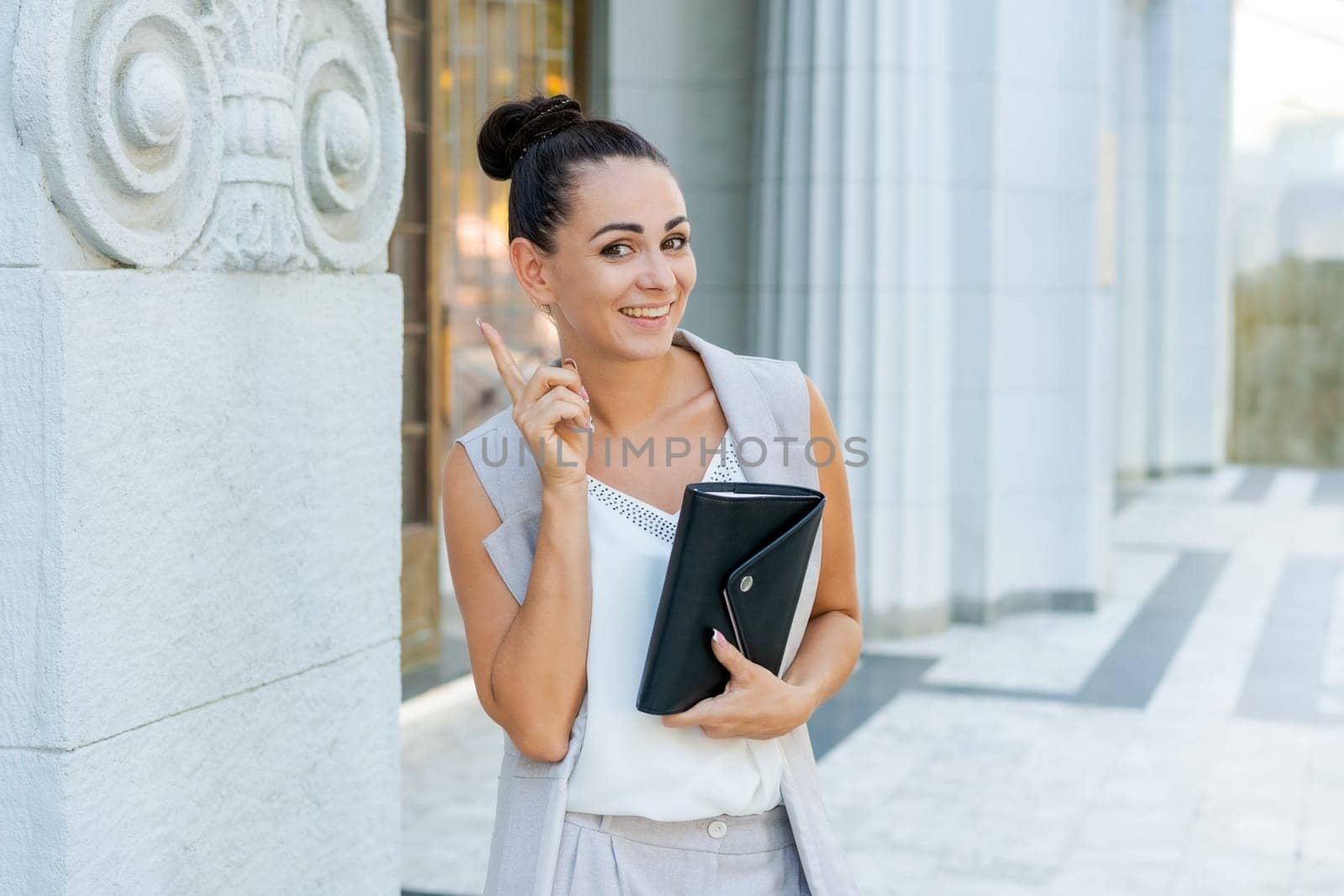 Successful businessman or entrepreneur smiling holding notepad while walking outdoor. City business woman working.