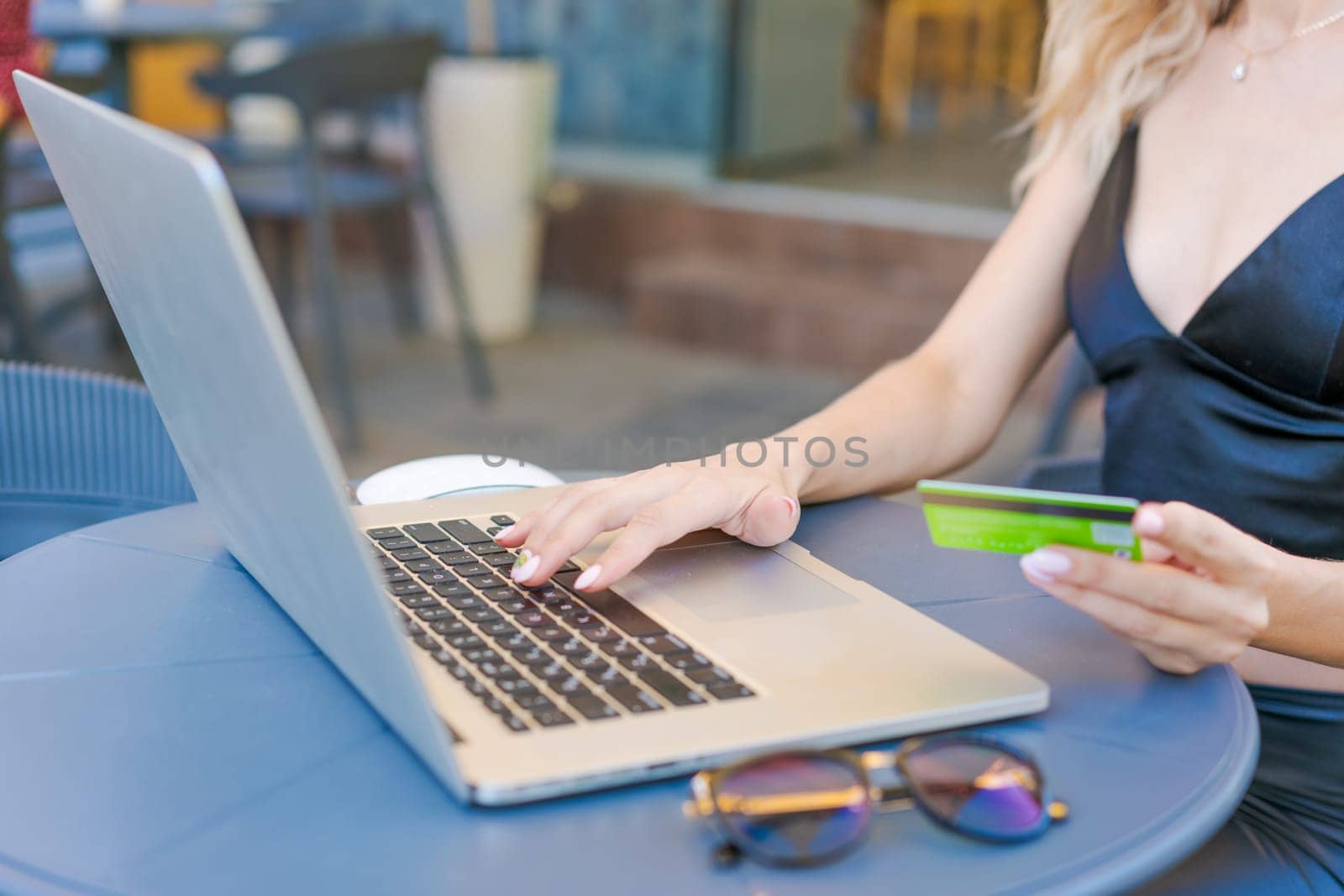 Female entrepreneur working on computer in cafe, doing online shopping with credit card in hand