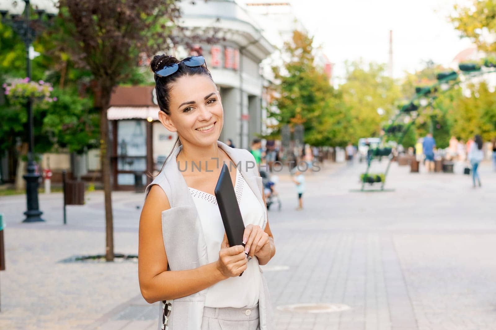 Successful businessman or entrepreneur smiling holding notepad while walking outdoor. City business woman working.