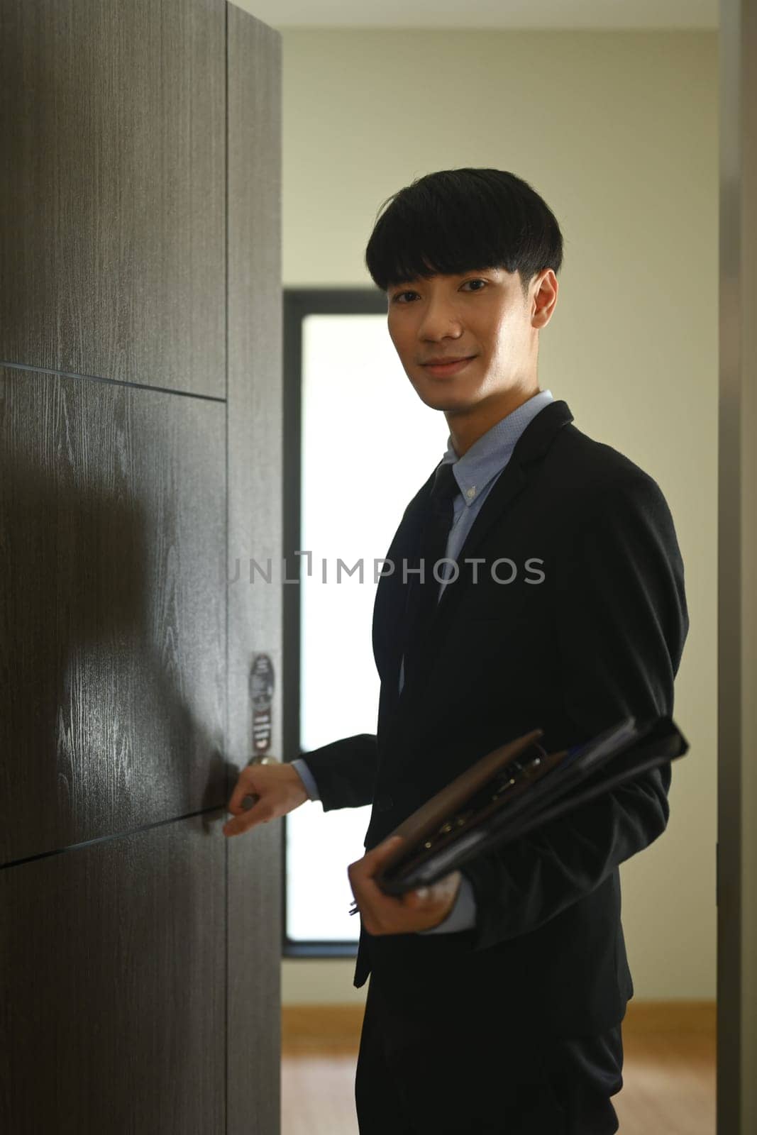 Smiling real estate agent opening the door of house for sale. Real estate mortgage and property investment concept.