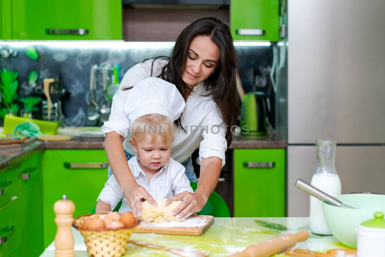 happy mother and son in the kitchen and making dough, family cooking concept