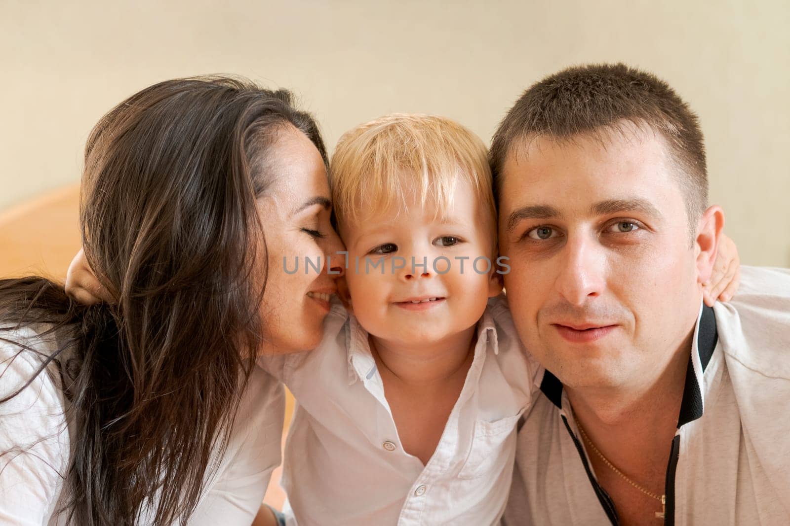 happy family lying on the bed and hugging, mom dad and little son