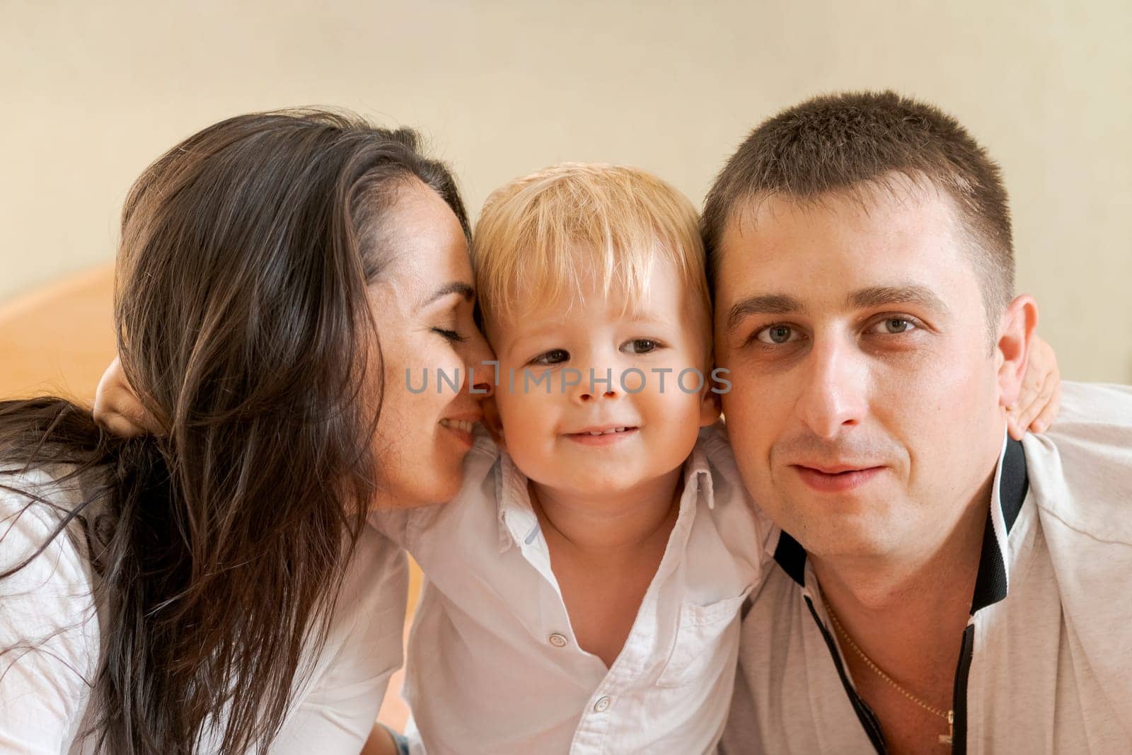 happy family lying on the bed and hugging, mom dad and little son by EkaterinaPereslavtseva