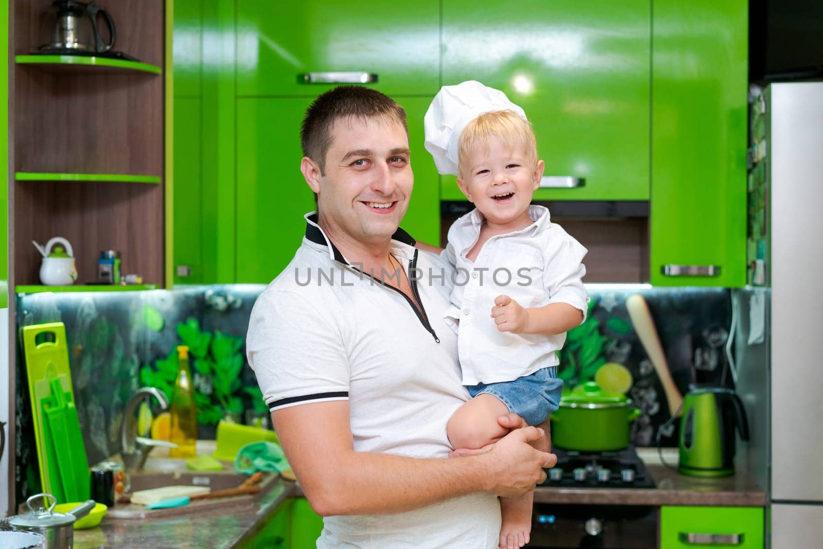 happy family, dad holding son in his arms in the kitchen