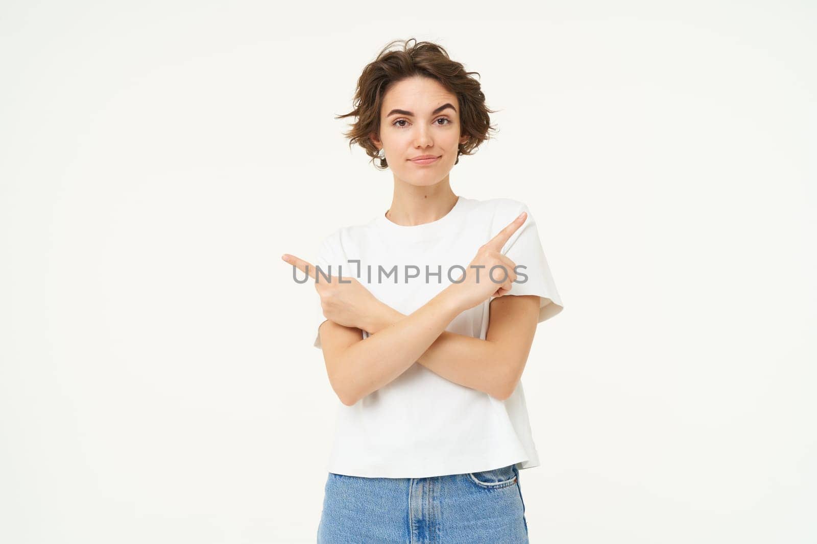 Puzzled woman makes choice, points fingers left and right, deciding, confused what to pick, stands over white studio background.