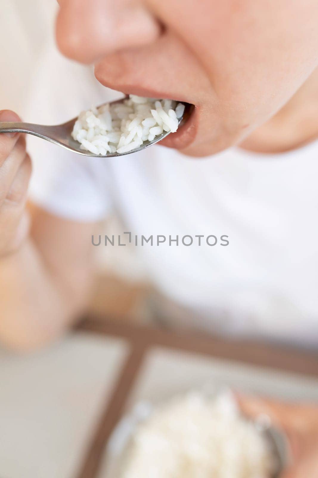 young woman brings a spoon of rice to her mouth.