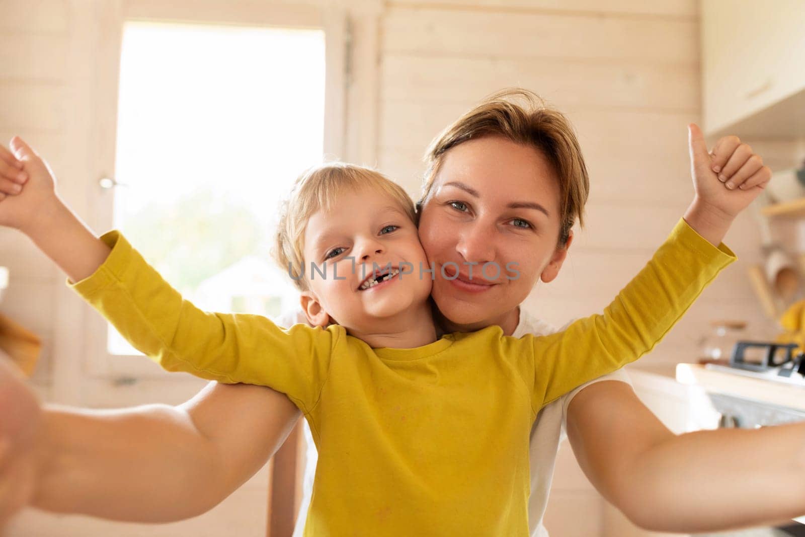 little Caucasian blond son and mother having breakfast with delicious food by TRMK