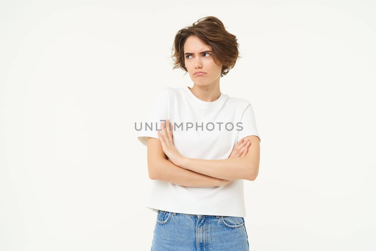Portrait of offended girl, student pouting, cross arms on chest and looking away, standing disappointed against white studio background by Benzoix