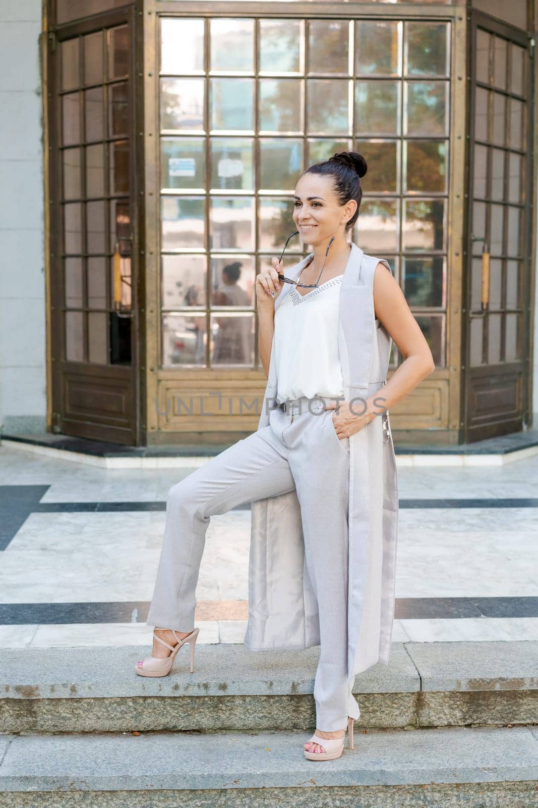 successful woman posing in a pantsuit on the steps of a building