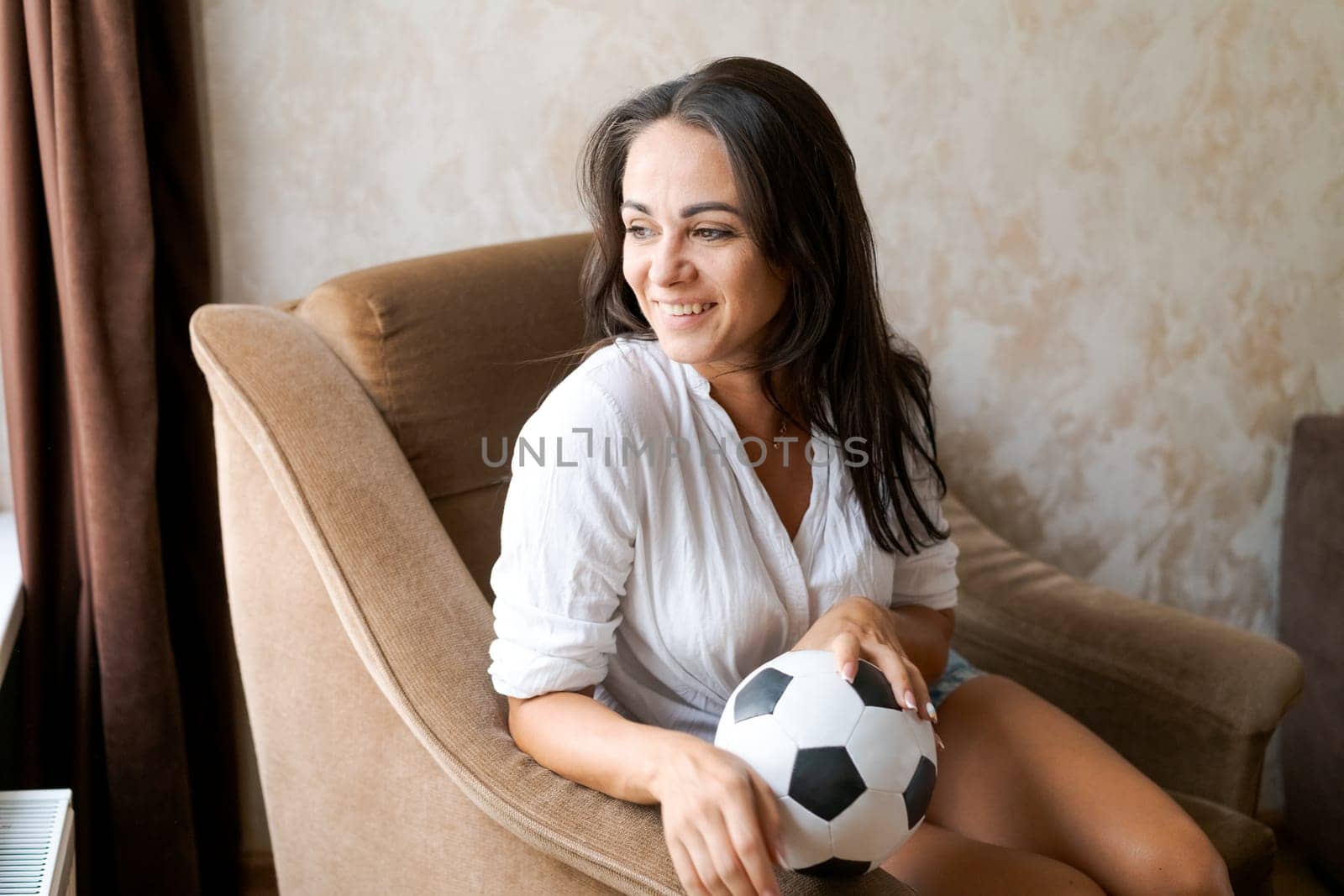 woman sitting on a chair holding a soccer ball in her hand by EkaterinaPereslavtseva