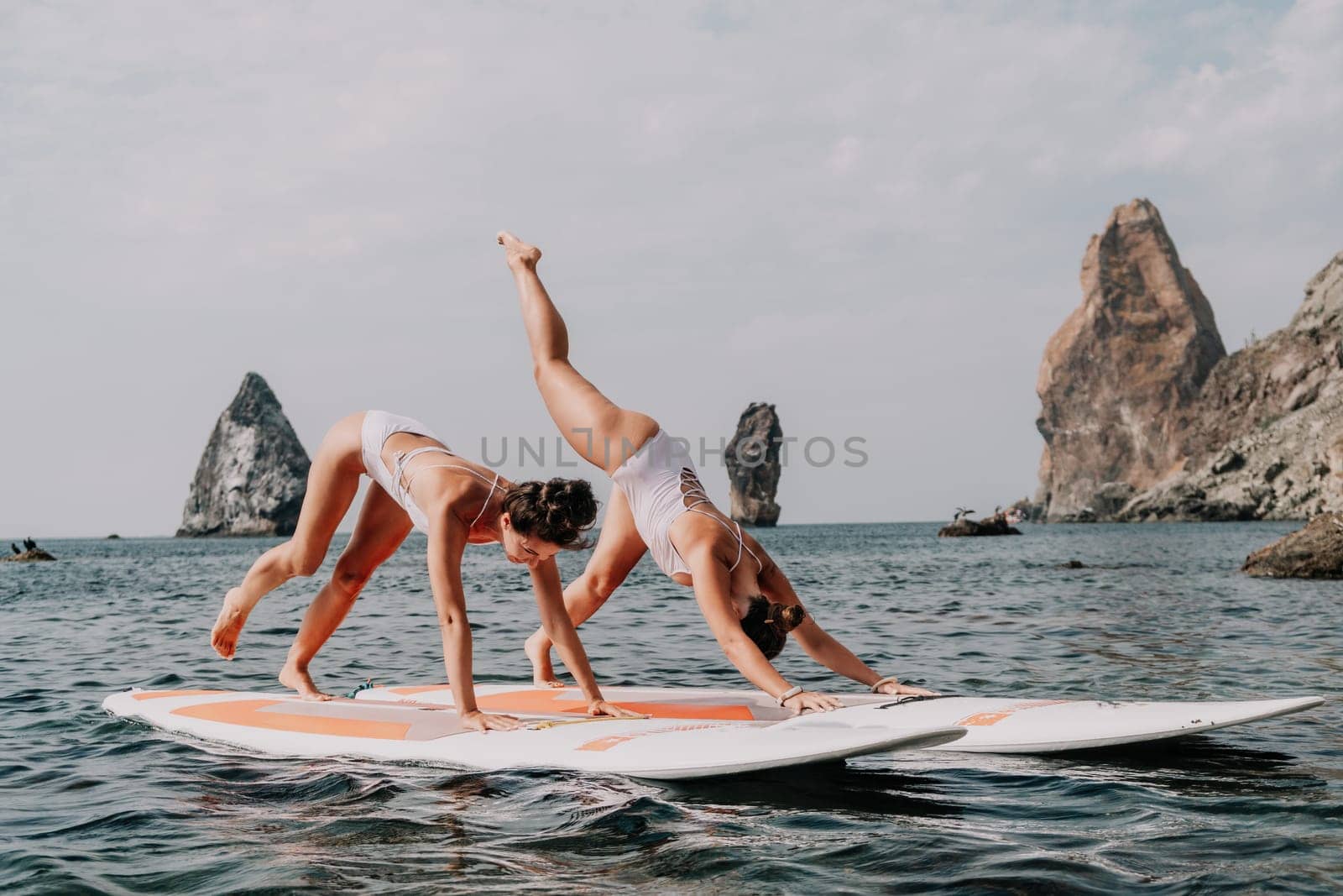 Woman sup yoga. Middle age sporty woman practising yoga pilates on paddle sup surfboard. Female stretching doing workout on sea water. Modern individual hipster outdoor summer sport activity