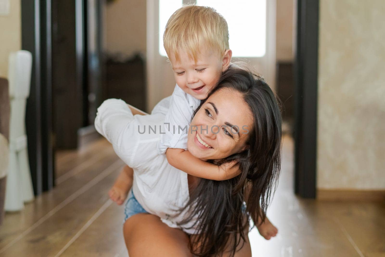 happy mother and son having fun sitting on the floor at home in the room
