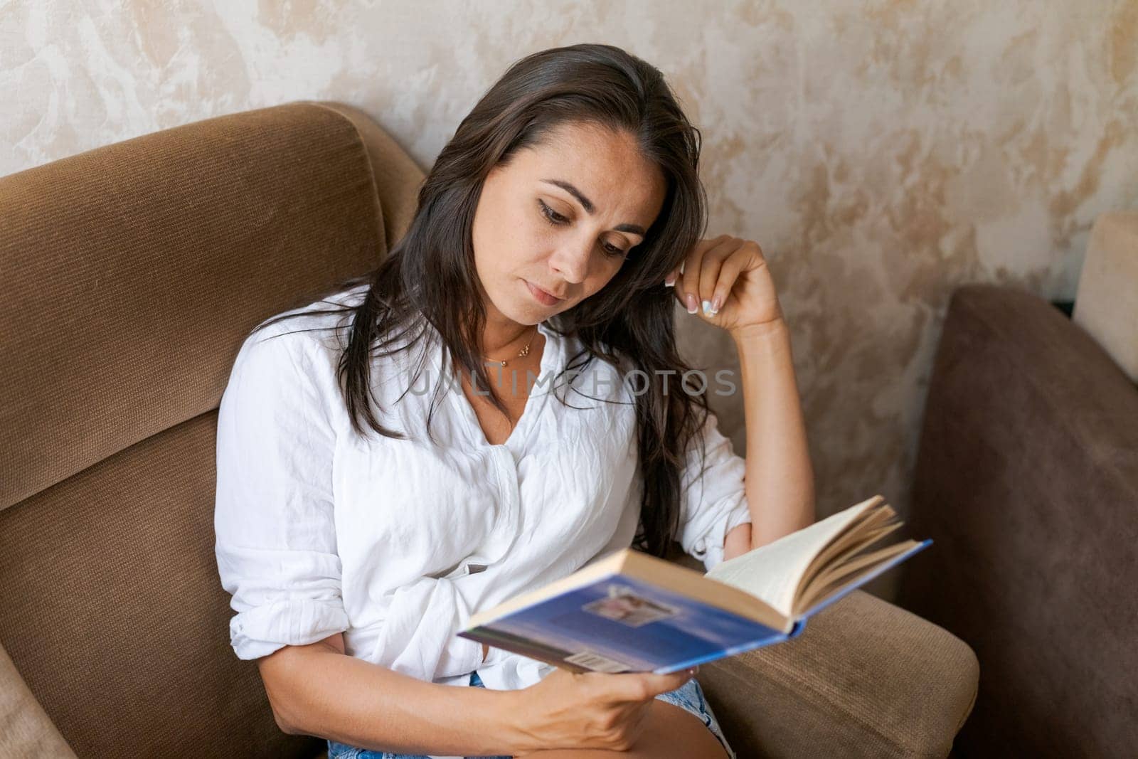 woman sitting on a chair holding a book in her hand, lifestyle concept by EkaterinaPereslavtseva