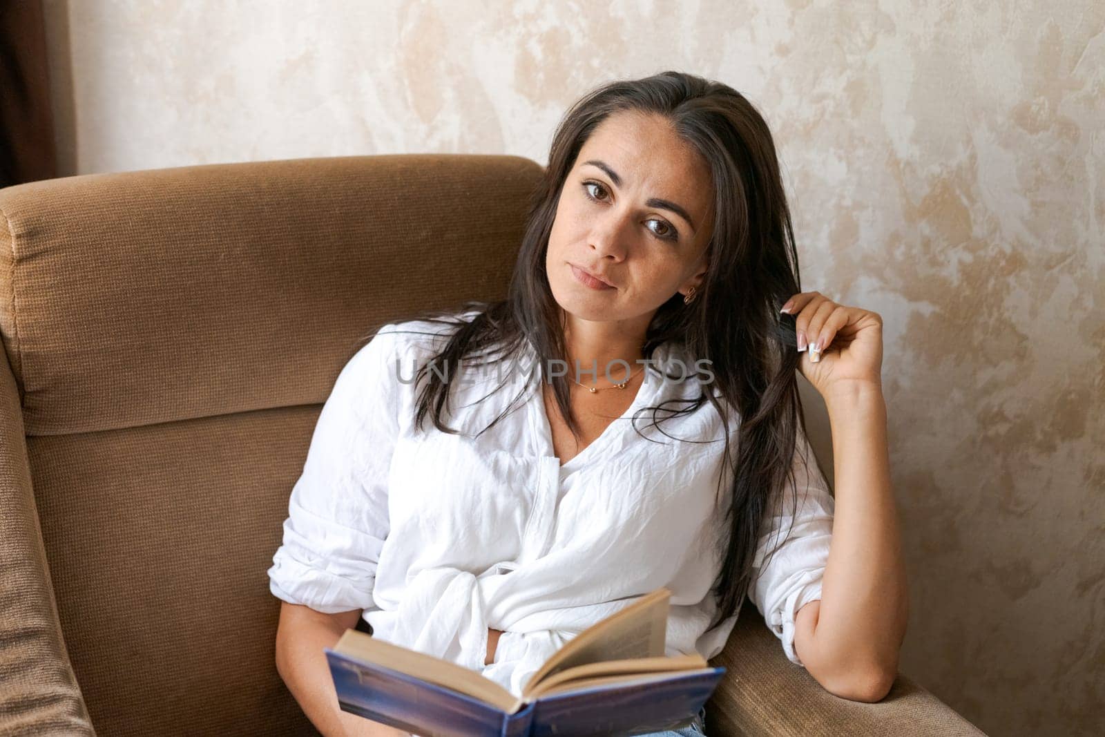 woman sitting on a chair holding a book in her hand, lifestyle concept