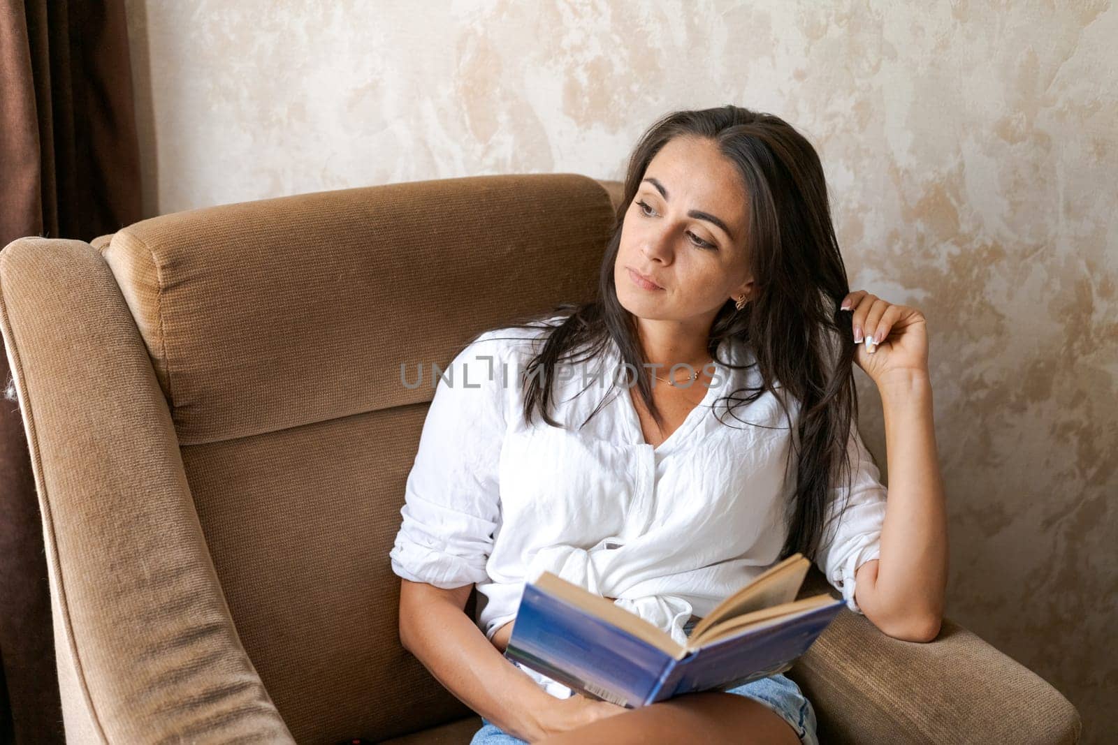 woman sitting on a chair holding a book in her hand, lifestyle concept