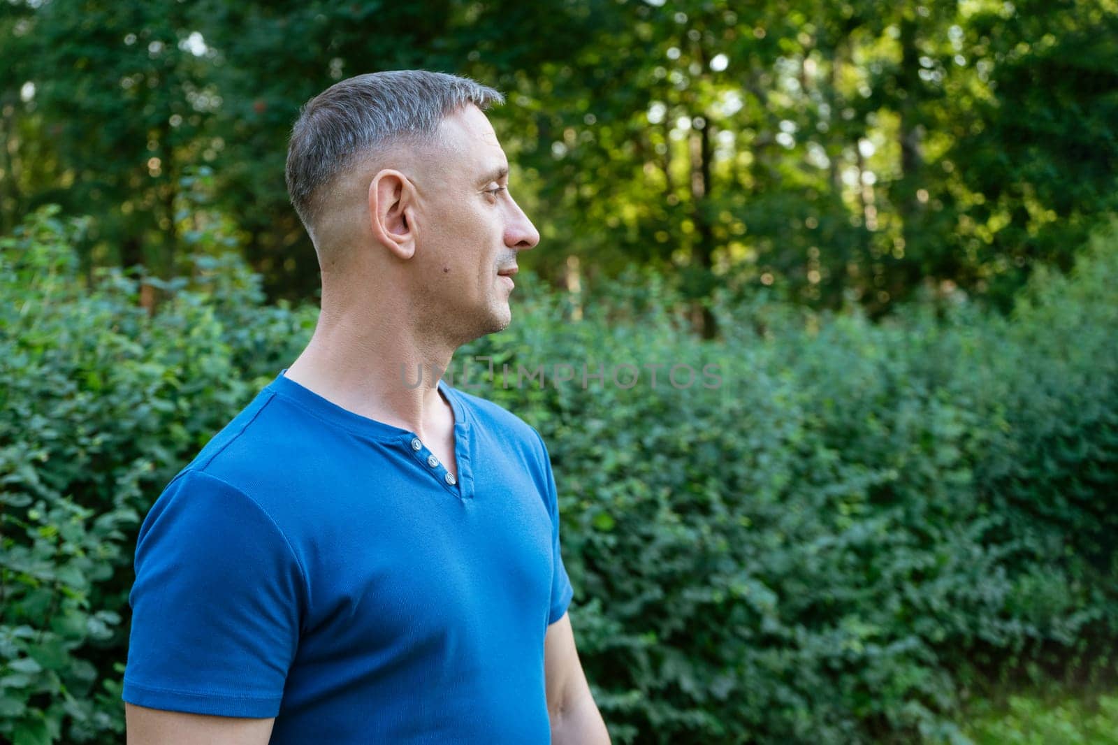 handsome portrait of a man in a blue T-shirt on a park