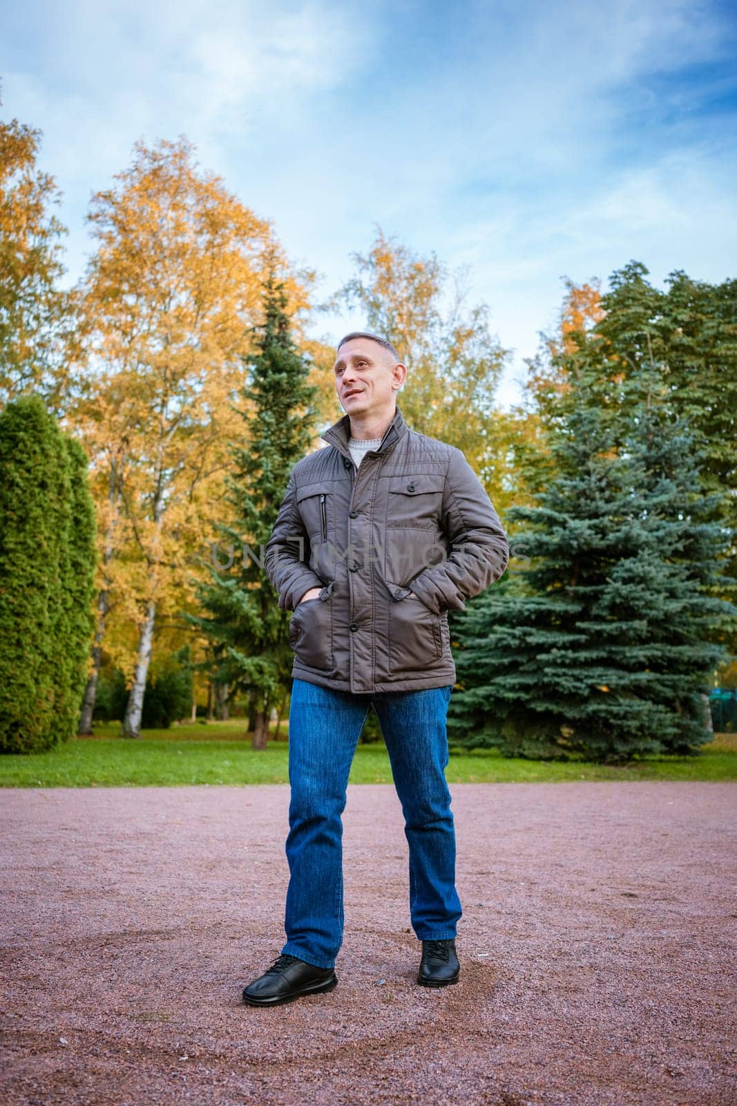 a man in an autumn jacket in the park stands on the path by EkaterinaPereslavtseva