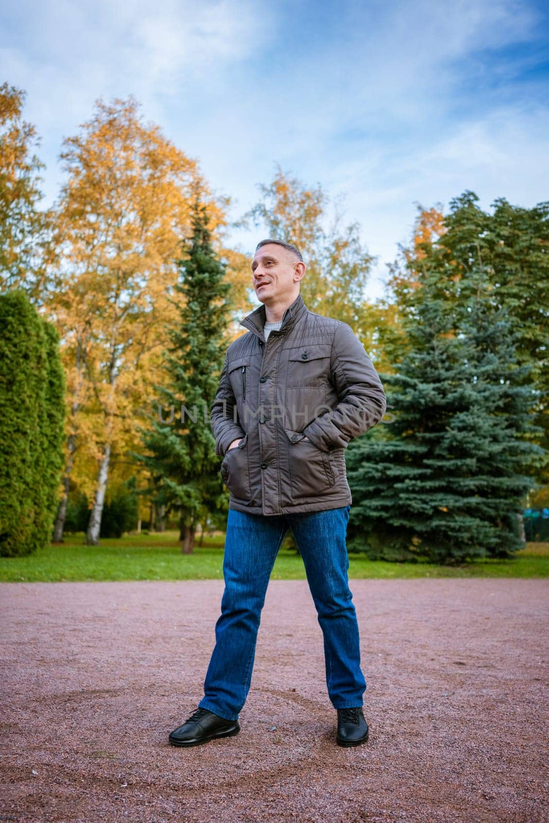 a man in an autumn jacket in the park stands on the path