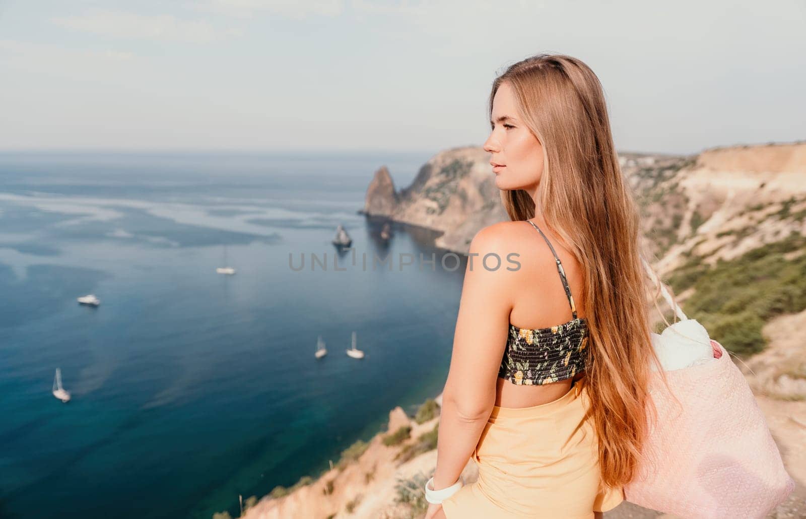 Woman travel sea. Happy tourist taking picture outdoors for memories. Woman traveler looks at the edge of the cliff on the sea bay of mountains, sharing travel adventure journey.