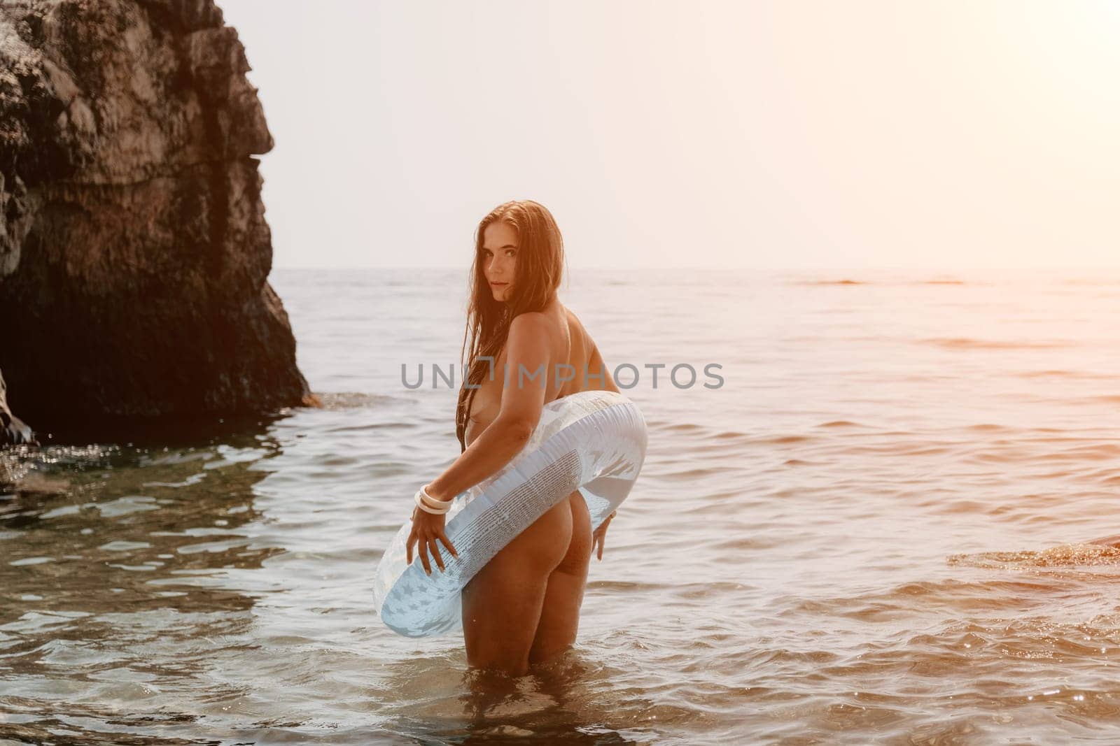 Woman summer sea. Happy woman swimming with inflatable donut on the beach in summer sunny day, surrounded by volcanic mountains. Summer vacation concept. by panophotograph