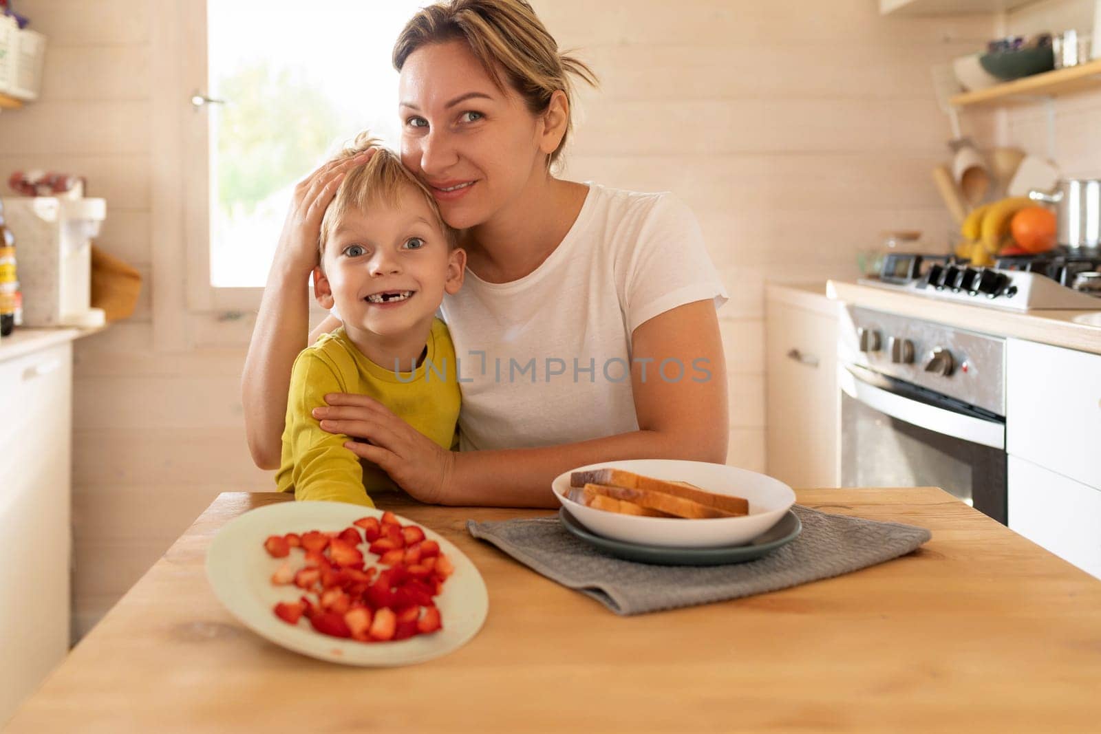 happy mother and little son preparing toast with strawberries for breakfast.