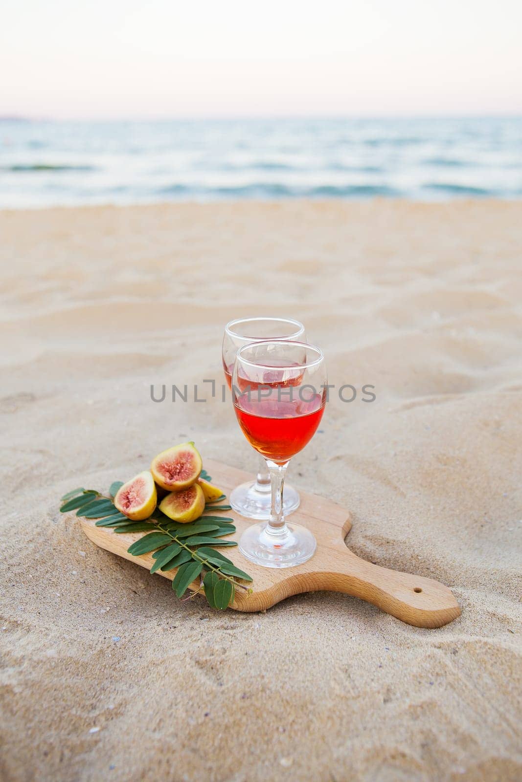 white cape, glasses on a wooden board and sand. Summer picnic close-up.