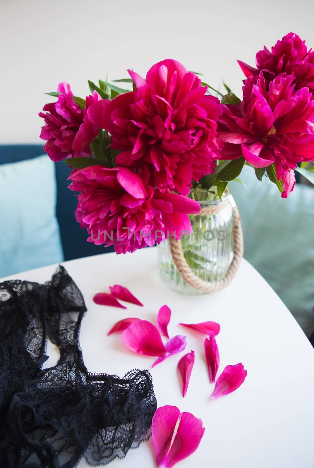 beautiful pink peonies near the window, petals crumble on the table, lace underwear.