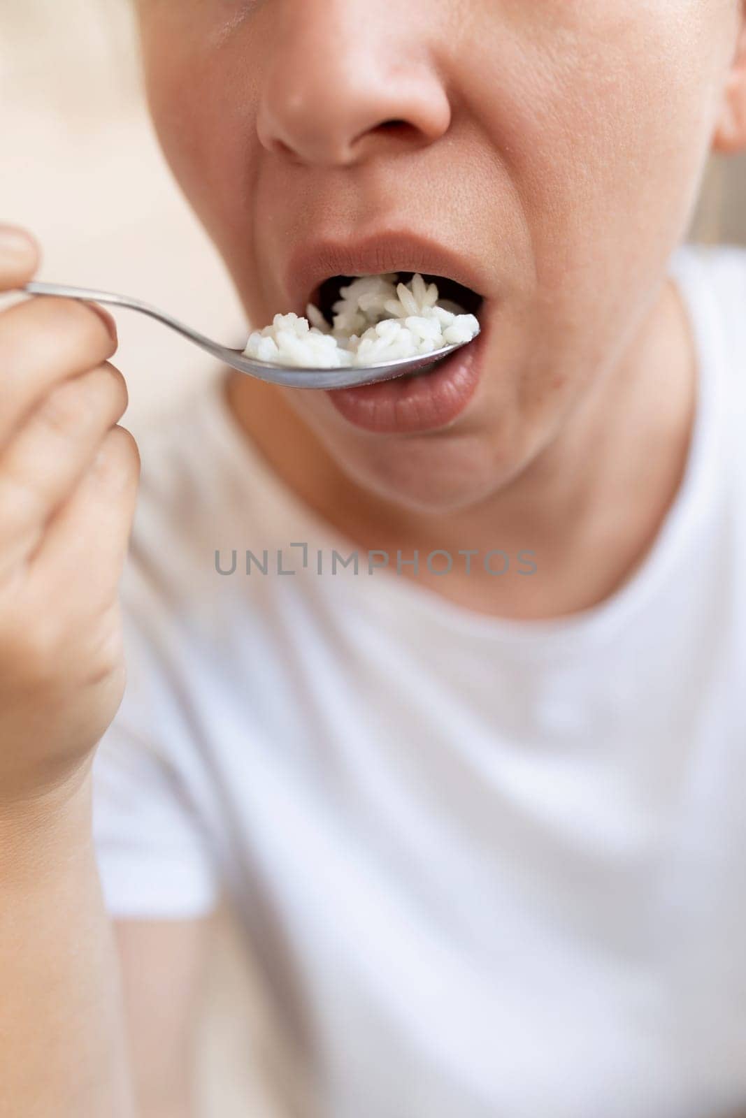 a woman stuffs a spoonful of rice into her mouth. concept of proper nutrition.
