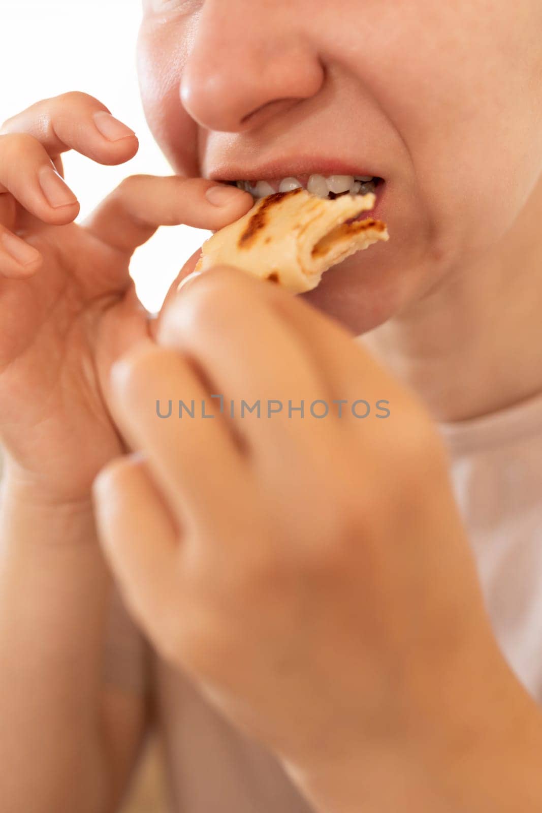 woman biting off flour pancakes during breakfast.