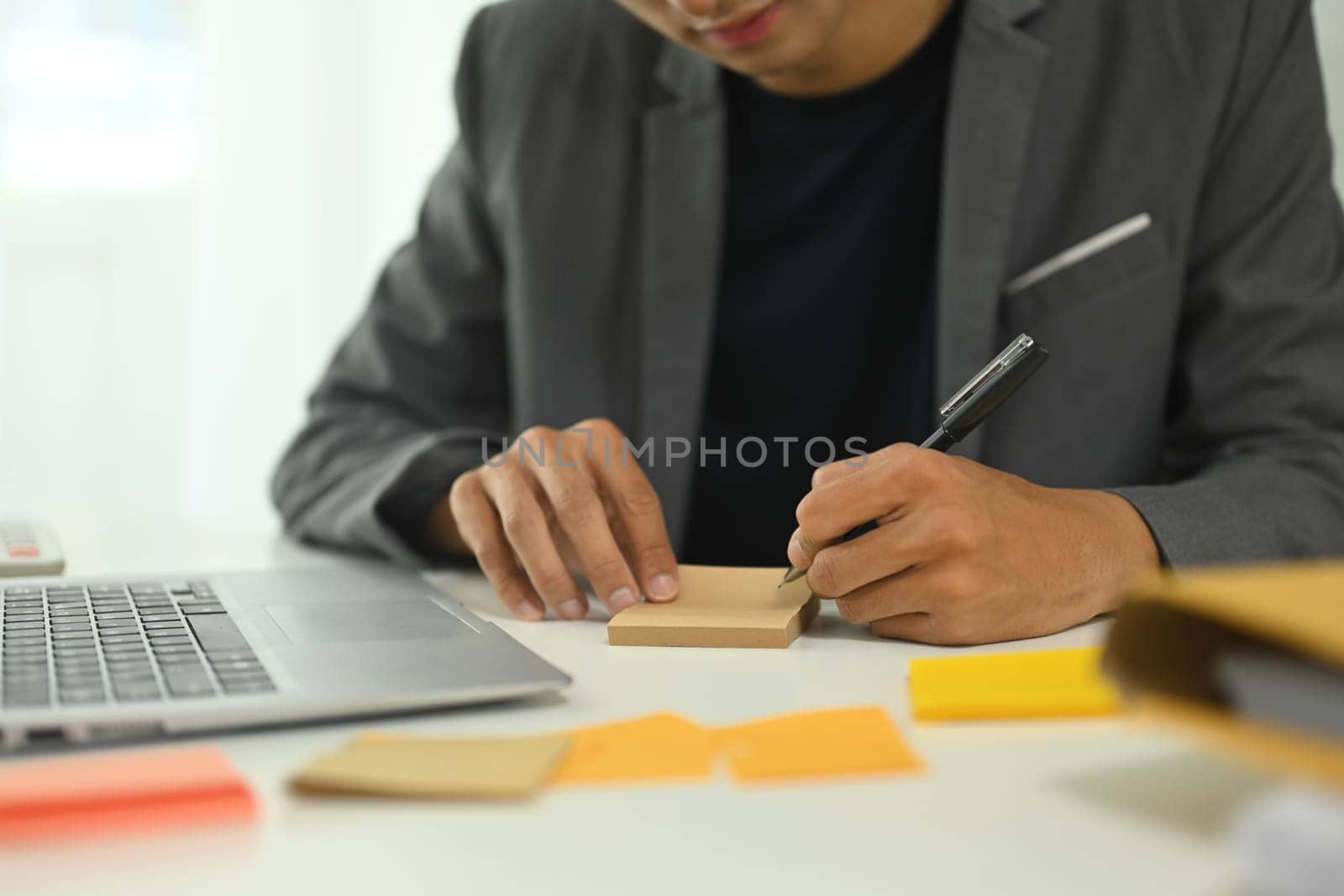 Focused businessman writing down ideas and planning tasks at desk.