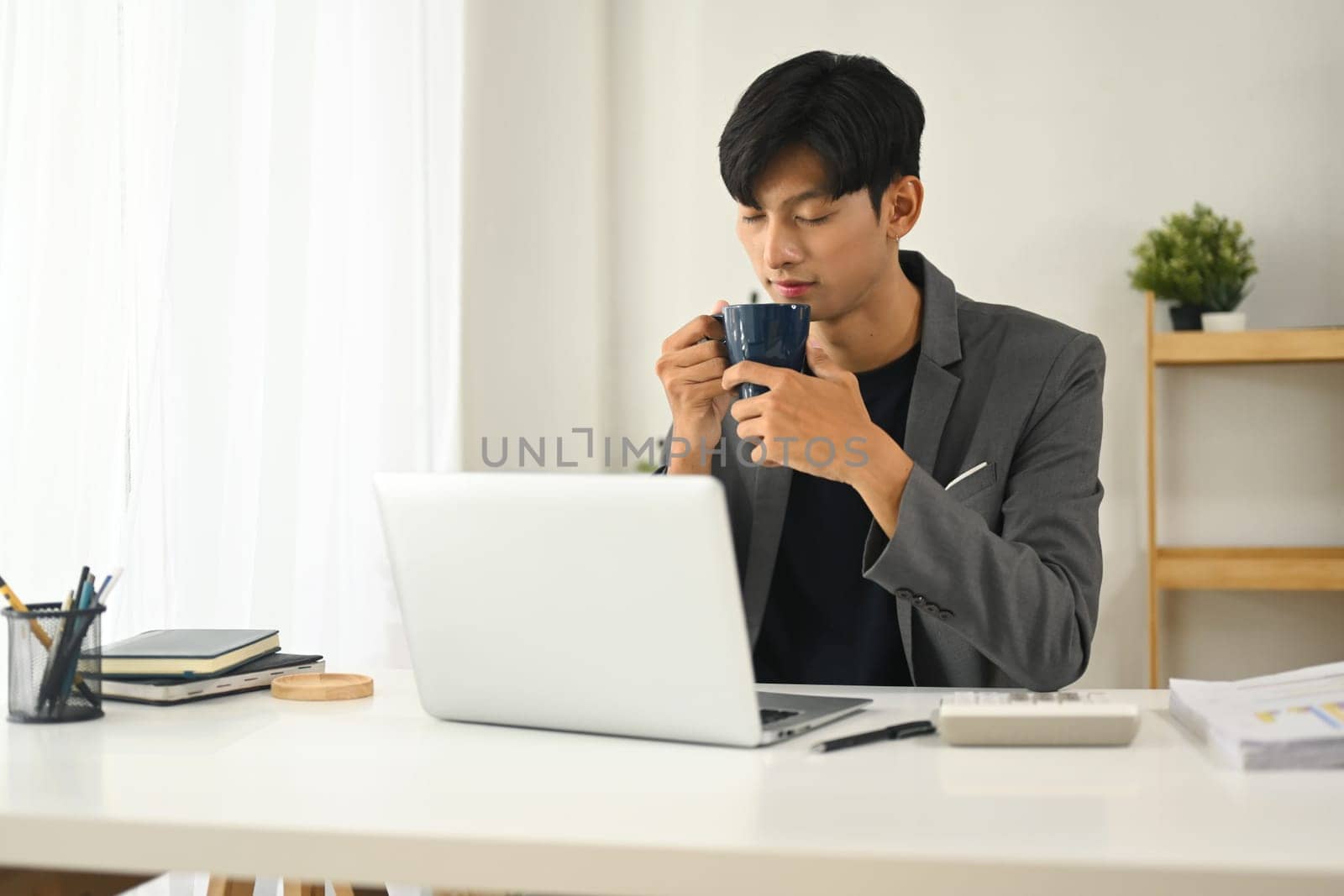 Young executive enjoying a peaceful coffee break at the desk.