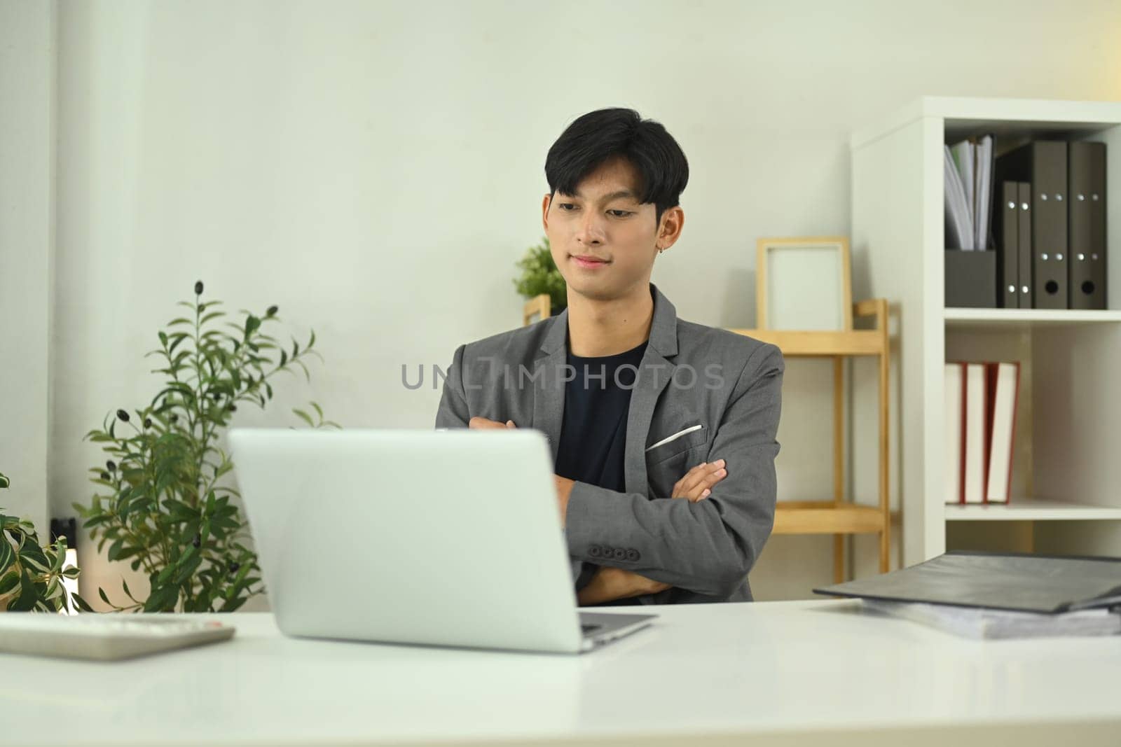 Young entrepreneur reviewing work on his laptop in modern office.