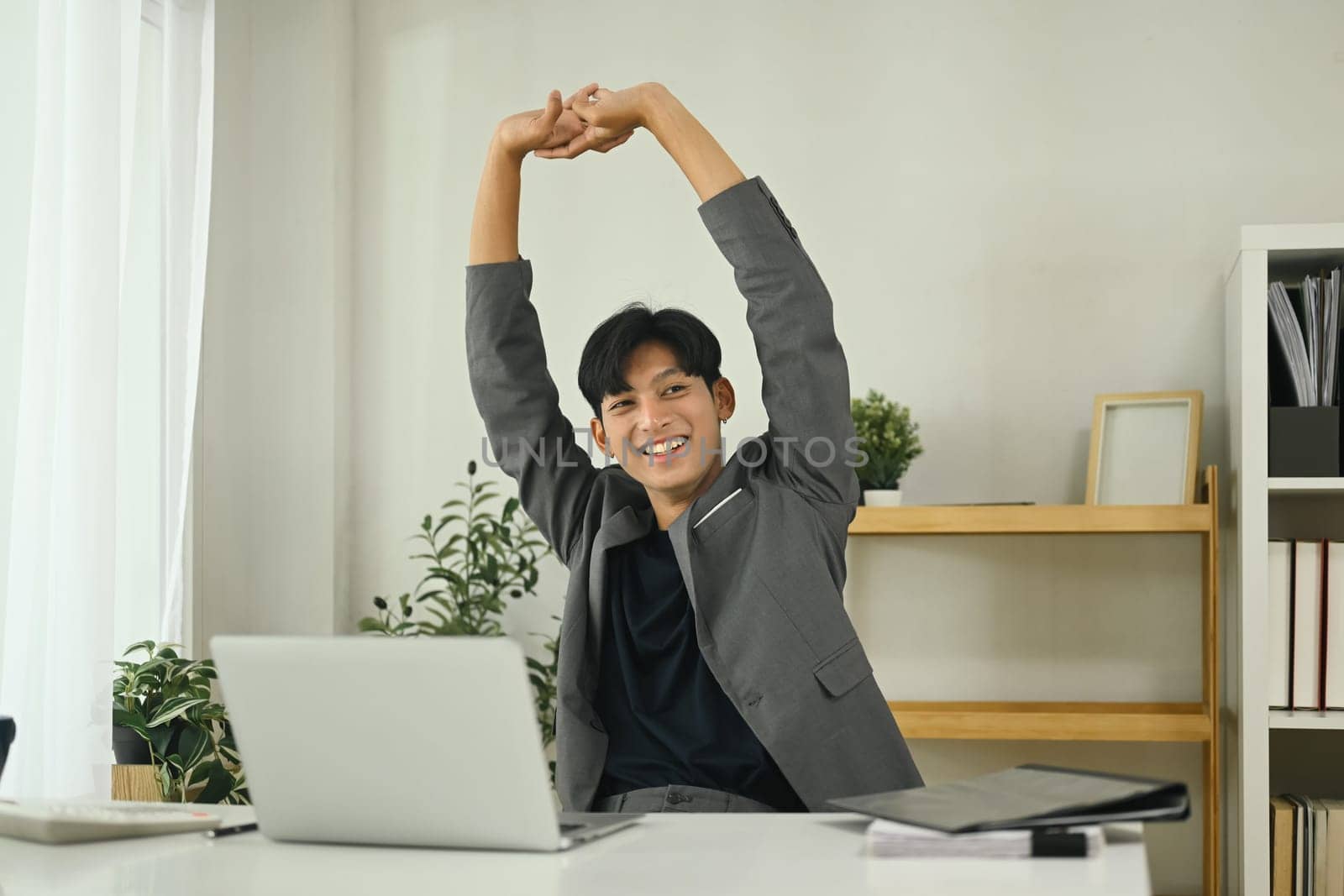 Relaxed office worker stretching after work session in the workplace.